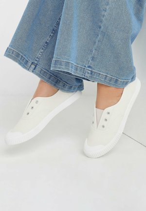 Hvide lærreds slip-on sko med elastiske sidelapper og tre metaløjer. Tekstureret hvid gummisål og rund tådesign.