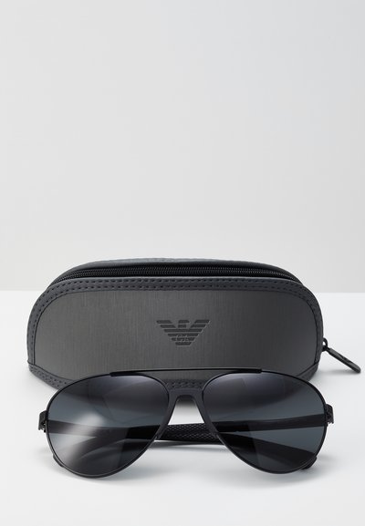 Ochelari de soare aviator negri cu lentile întunecate, cadru metalic și accente din cauciuc texturat. Include un toc dur gri cu logo.