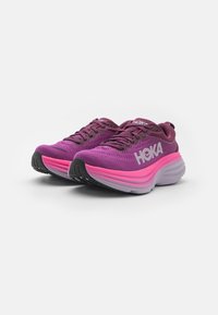 Scarpe da corsa viola con tomaia in rete, accenti rosa, suola spessa e logo HOKA di lato. Suola in gomma nera con texture per una presa ottimale.