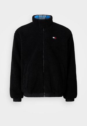 Veste polaire noire zippée entièrement, col montant, poignets élastiques, poches latérales et petit logo Tommy Jeans sur la poitrine gauche.