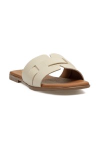 Sandalias deslizantes de cuero beige con punta abierta, que cuentan con un diseño trenzado en la parte superior y una suela plana en tono tostado. Textura suave y estilo casual.