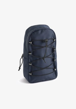 Tamsiai mėlyna kuprinė, pagaminta iš tekstūruoto audinio, su elastingomis virvėmis priekinėje dalyje ir užtrauktuku viršuje.