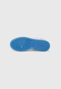 Vit sneakersula med cirkulära och linjära mönster. Har en ljusblå bas med texturerat grepp för bra fäste. Nike-logotyp synlig.