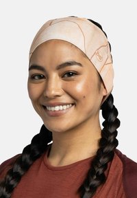 La cinta para la cabeza Buff presenta un color durazno claro con sutiles patrones marmoleados, confeccionada con tela elástica que se ajusta cómodamente alrededor de la cabeza.