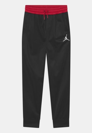 Pantalon de sport noir avec ceinture élastique rouge et cordon de serrage, arborant un logo Jumpman blanc sur la cuisse droite.