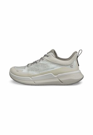 Scarpa sportiva grigia chiara con tomaia in rete, suola in gomma, chiusura con lacci e accentuazione del logo. Presenta un tallone testurizzato e un design traspirante.
