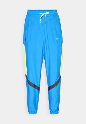 Pantalones deportivos Nike en azul brillante con cintura elástica y acentos de malla amarilla. Presenta rayas diagonales negras a lo largo de las piernas. Material ligero.