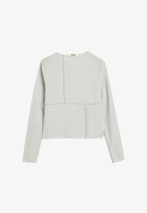 Top corto de manga larga gris claro hecho de un tejido texturizado, que presenta un diseño de patchwork único con paneles de diferentes formas y detalles de costura.