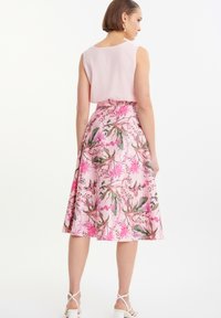 Vestito floreale con corpino aderente e gonna svasata, in morbido rosa con motivi floreali multicolori. Rifinito con una cintura e una leggera lucentezza.