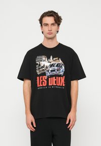 Čierne bavlnené tričko s grafickou potlačou áut a červeným textom "LES DEUX". Boxy strih s krátkymi rukávmi a okrúhlym výstrihom.