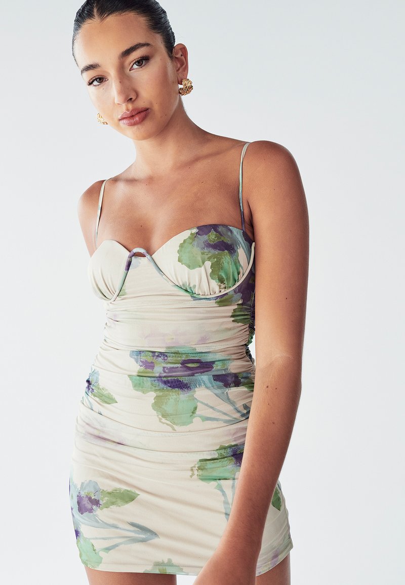 Bloemige bodycon jurk in crème met groene en paarse aquarel patronen, zachte stof, aansluitend ontwerp en dunne banden.
