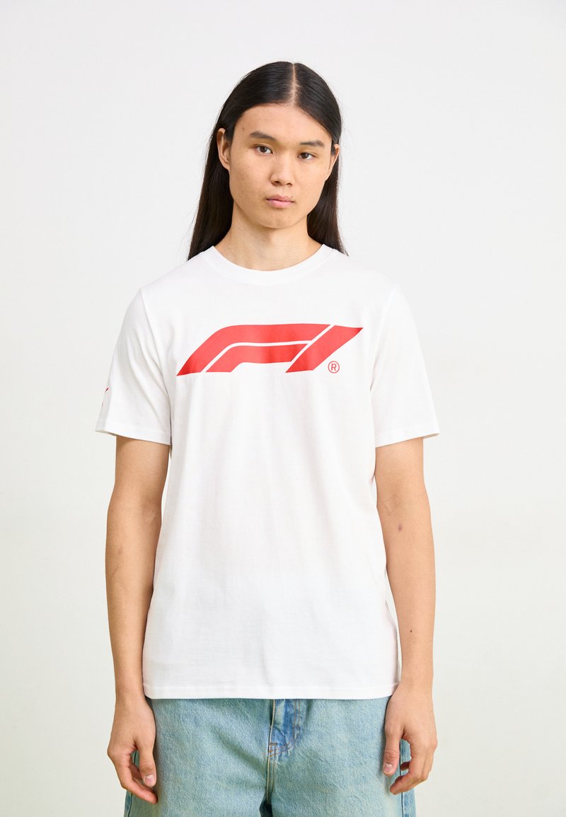 Balts kokvilnas T-krekls ar lielu sarkanu Formula 1 logo priekšā. Īsas piedurknes un apaļa kakla izgriezums. Ikdienišķa, brīva piegrieze.
