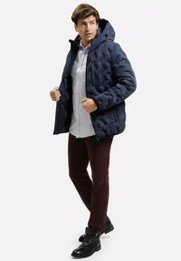 Granatowa pikowana kurtka puchowa z kapturem, z przodu na zamek błyskawiczny i elastycznymi mankietami. Nosi się ją na lekką koszulę, w połączeniu z ciemnymi spodniami i czarnymi botkami.
