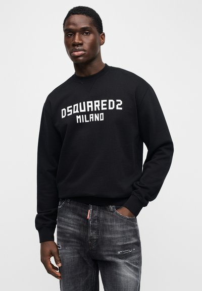 Schwarzer Pullover mit dem Aufdruck "DSQUARED2 MILANO" in Weiß. Verfügt über einen Rundhalsausschnitt und gerippte Bündchen. Kombiniert mit verwaschenen grauen Jeans.