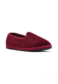 Chausson slip-on en bourgogne doux avec une semelle texturée et un point décoratif autour de la base, incliné pour montrer le côté et le dessus.