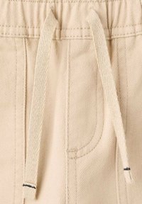 Bežna tkanina s teksturiranim zaključkom, z elastičnim pasom in vrvico, z majhnim žepom na strani.