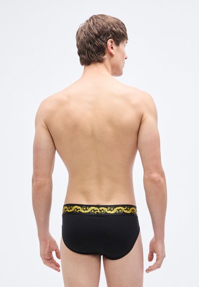 Slip de bain noir avec une ceinture décorative à motif doré, texture lisse, coupe ajustée, sans ornements supplémentaires.