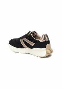 Zapatillas negras con acentos dorados, que cuentan con un diseño de tela texturizada, un cuello acolchado y una suela blanca con un talón estriado.