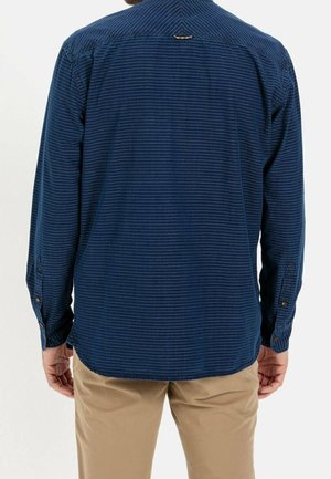 Camicia a maniche lunghe blu navy con un sottile motivo a righe, caratterizzata da un orlo arrotondato e dettagli con una sola abbottonatura ai polsi.