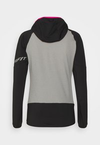 Hooded atletska jakna sivo tijelo i crne rukave. Ima ružičastu unutrašnjost kapuljače i "GAFIT" logo na lijevom rukavu. Glatka tekstura tkanine.