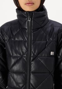 Czarna ocieplana kurtka z sztucznej skóry, z wysokim kołnierzem, diagonalnym wzorem pikowania i zapięciem na zamek błyskawiczny z akcentem logo.