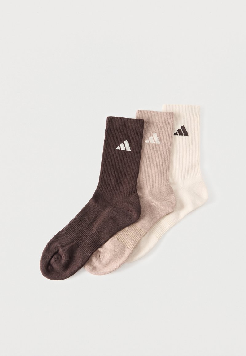 Trois chaussettes montantes côtelées en marron foncé, beige et blanc cassé, chacune avec un petit logo triangulaire sur le dessus.