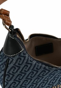 Sac à main bleu marine en denim texturé, avec une fermeture éclair, des accents en cuir noir et une bandoulière beige, intérieur dans une teinte plus claire.