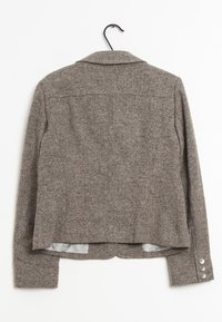 Hnědý blazer s rybí kostrou, klasickým límcem, knoflíkovými manžetami a strukturovaným designem, vyrobený z texturované tkaniny.