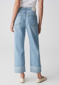 Jeans a gamba larga in denim azzurro chiaro con una finitura sbiadita, dotati di tasche posteriori, orlo risvoltato e un'etichetta bianca in vita.