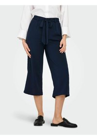 Pantalon culotte bleu marine en tissu léger, avec une taille nouée et une longueur raccourcie. Texture lisse avec une coupe décontractée.