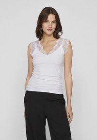 Witte tanktop met kantaccenten langs de schouders en de halslijn, met een getailleerd ontwerp en geribbeld textuur. Gekozen in combinatie met zwarte broek.