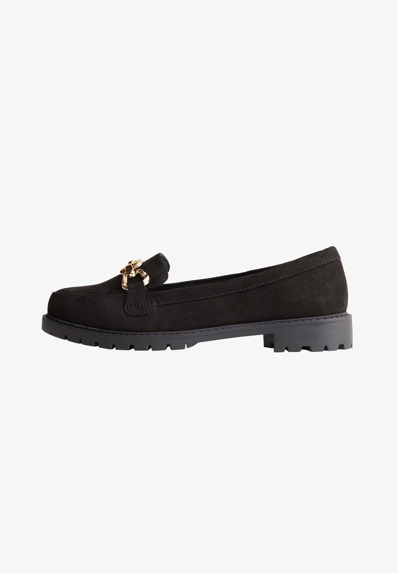 Mocassin en daim noir avec semelle épaisse et accent chaîne dorée sur le dessus, vue latérale sur fond blanc.