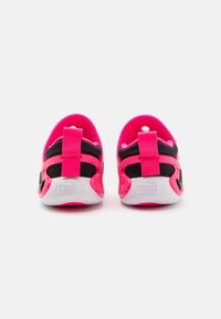 Rosa och svarta sportskor med en flexibel design, som har ett mjukt material, kontrasterande detaljer och framträdande vit logotyp på hälen.