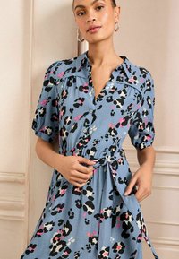 Rochie albastră cu butoni, cu mâneci scurte tip puff; prezintă un imprimeu leopard multicolor și un cordon la talie pentru o ajustare personalizată.