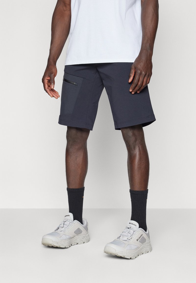 Navy shorts featuring a side zip pocket, made from a lightweight material. Paired with grey sports shoes and black crew socks.