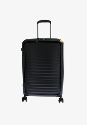 Valise rigide noire avec texture nervurée, poignée rétractable, roues doubles et un accent jaune dans le coin supérieur.