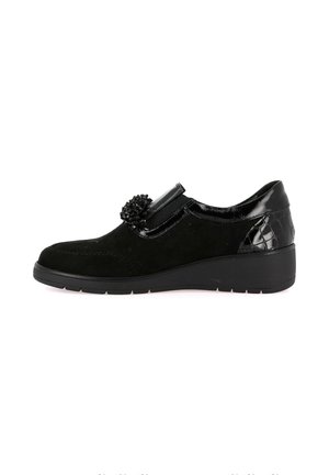 Scarpa in suede nero con dettaglio in pelle verniciata liscia, decorazione con pon-pon e suola a zeppa bassa. Punta dalla forma arrotondata.