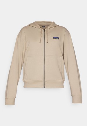 Béžová mikina na zip s přední kapsou, nastavitelnou kapucí s tkaničkou a malým logem na levém prsou. Měkká tkanina s žebrovanými manžetami.