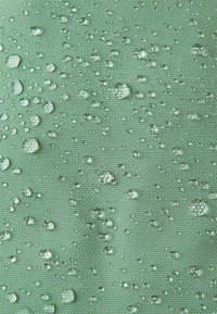 Tessuto verde texturizzato con gocce d'acqua. La superficie presenta gocce di diverse dimensioni, ad indicare la resistenza all'acqua.