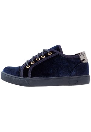 Marineblauwe suède veter sneaker met gouden veterogen, zwarte rubberen zool en glanzende zwarte hielaccent.