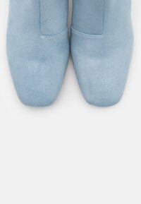 Hellblaue Wildleder-Stiefeletten mit spitzen Zehen, minimaler Nahtführung und glatter Textur. Keine sichtbaren Beschläge oder auffälligen Muster.