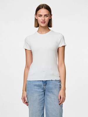 Camiseta blanca de manga corta con dobladillo en ondas. La tela parece suave y ajustada, combinada con jeans de tiro alto en un tono azul claro.