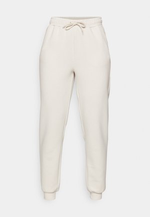 Lys beige joggebukser laget av myk stoff, med elastisk linning med snor, sidelommer og tapered mansjetter ved anklene.