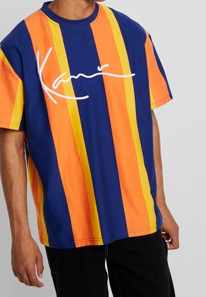 Camiseta de manga corta con rayas verticales en azul, naranja y amarillo. Presenta una firma bordada en blanco en la parte frontal. Material de algodón.