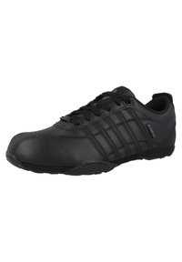 Chaussure de sport noire avec une tige en cuir lisse, un design à lacets et trois bandes proéminentes sur le côté. Semelle en caoutchouc pour une bonne traction.