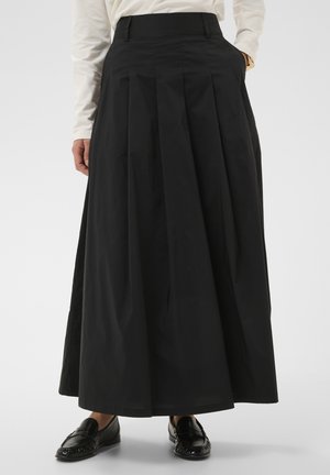 Mustast kerge kangaga plisseeritud maxi seelik, millel on kõrge vöökoht ja küljetaskud, sobitatud mustade loafer-kingadega.