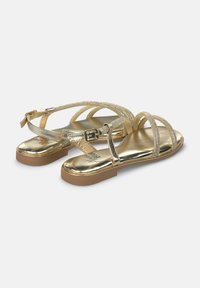 Sandali dorati con cinturini, dotati di soletta piatta e caratterizzati da cinturini metallici testurizzati e chiusura a fibbia. Superficie interna liscia con suola di colore marrone chiaro.