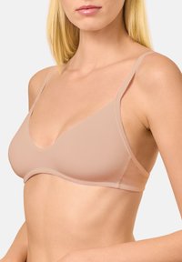 Bralette acolchado en tono nude claro, confeccionado en tejido suave. Presenta un escote en V profundo, tirantes delgados ajustables y bordes sin costuras.