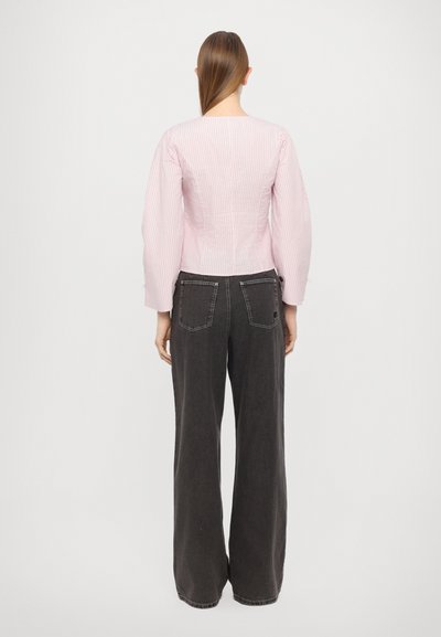 Ljusrosa randig blus med puffärmar, figursydd bodice och öppen rygg. Kombination med högmidjade, vida svarta jeans med fickor.