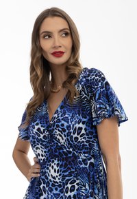 Rochie din material cu imprimeu animalier albastru, cu mâneci scurte și volane, design înfășurat și material ușor. Conține diverse nuanțe de albastru, negru și alb.
